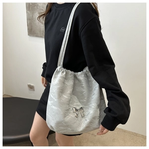 Detail of silver bucket bag with metallic crinkle texture and delicate bow ornament