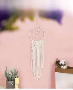 Detail of white cotton moon dreamcatcher with long tassels on a pink backdrop