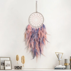 Pink and purple dream catcher with feathers and beads hanging as wall decor