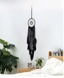 Detail of a black Bohemian dream catcher with feathers and Tree of Life on a white wall