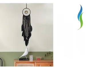 Detail of bohemian black woven dreamcatcher with feathers and wooden beads on wall