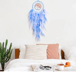 Detail of blue Tree of Life dreamcatcher with feathers hanging on a cozy bedroom wall