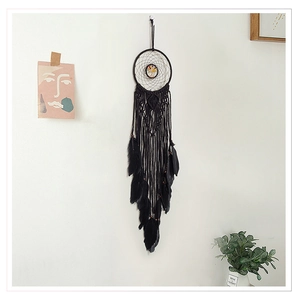 Detail of black macrame dreamcatcher with tree of life stone and hanging feathers