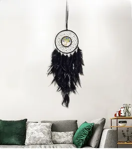 Detail of double-ring dreamcatcher with tree of life and black feathers on white wall