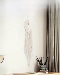 Detail of handmade moon dreamcatcher with white feathers, cotton tassels and wood beads