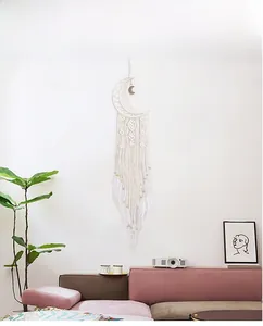 Boho moon dream catcher with white feathers and tassels hanging on a living room wall