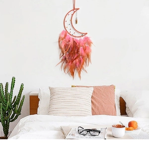 Close-up of moon dream catcher with gradient pink feathers and crystal pendant