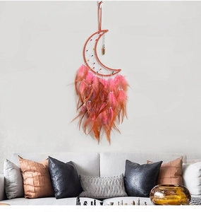 Detail of moon-shaped dream catcher with feathers hanging over a modern sofa