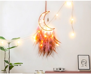 Detail of moon dreamcatcher hanging with warm LED lights and pink gradient feathers