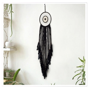 Close-up of black cotton dreamcatcher with woven net, feathers and wooden beads