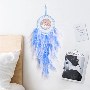 Blue Tree of Life dreamcatcher with natural feathers hanging in a cozy bedroom