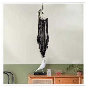 Détail d'un attrape-rêves lune noire avec plumes pour décoration murale bohème chic