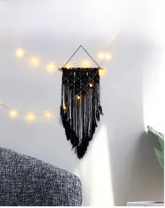 Macro detail of Nordic black macrame wall hanging with feathers and woven cotton rope