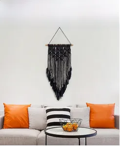 Detailed close-up of a large black handmade bohemian dreamcatcher with feathers on wall