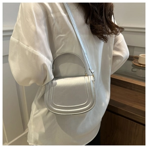 Silver metallic saddle bag with decorative stitching and dual-use handle straps