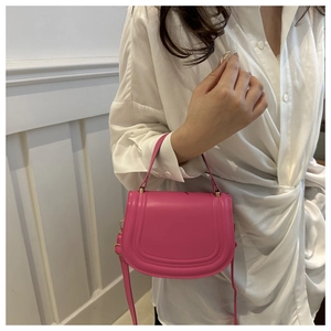 Detail of magenta faux leather saddle bag with gold hardware on white background