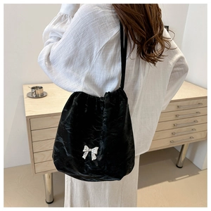 Large black drawstring bucket bag with silver bow accent shown on model shoulder