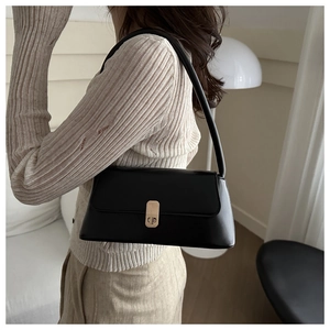 Detail of a vintage black matte leather shoulder bag with a gold metal twist lock