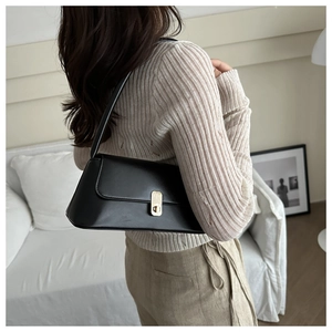 Gros plan d'un sac baguette noir minimaliste avec une boucle en métal doré vintage