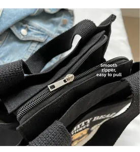Detail of smooth metal zipper closure on a black canvas tote with cartoon bear print