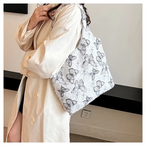 Detail of white butterfly print tote bag with frayed edges worn by a model