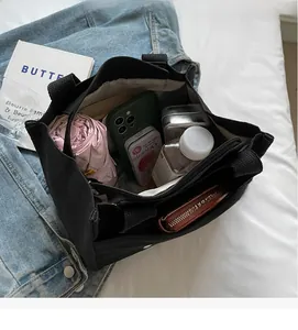 Interior view of black canvas tote bag showing large capacity for umbrella and phone
