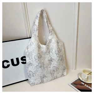 Detail of white butterfly print tote bag with frayed edges on a minimalist desk