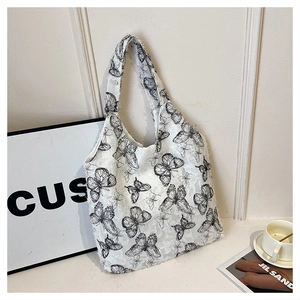 Close-up of white lace shoulder bag with butterfly print leaning against a textured wall