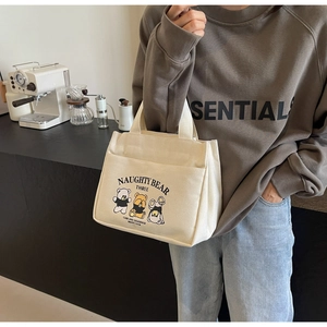 Detail of canvas tote bag featuring cute cartoon bear prints and sturdy top handles