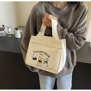 Close-up of beige canvas tote bag featuring cute cartoon bears and zipper closure detail