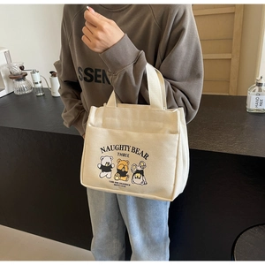 Close-up of cream canvas tote bag with cute cartoon bear prints and front pocket detail