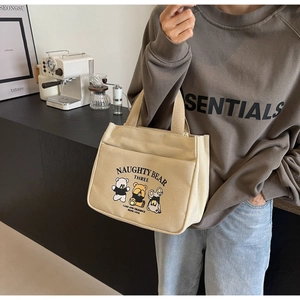 Detail of cute cartoon bear print and front pocket on beige canvas tote lunch bag