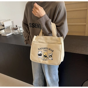 Detail of canvas tote bag featuring cute cartoon bear prints and front storage pocket