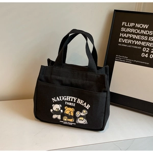 Detail of black canvas tote bag with cartoon bears and side view on marble surface
