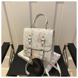 Close-up of white leather handbag with pink butterfly prints and double buckle details