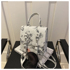 Detail of white mini square bag featuring black butterfly prints and dual buckle straps