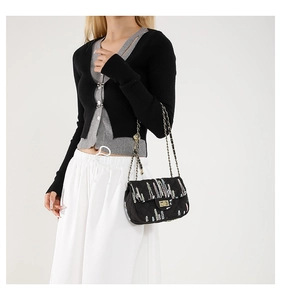 Close-up of black quilted crossbody bag featuring colorful embroidery and gold chain strap