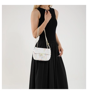 Detail of white quilted crossbody bag with colorful stripes and gold chain strap