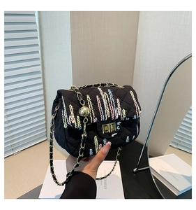 Detail of black quilted crossbody bag with colorful stripes and golden chain strap