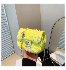 Detail of yellow quilted fabric shoulder bag with gold chain strap and metal lock