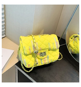Detail of yellow quilted crossbody bag with colorful embroidery and golden chain strap