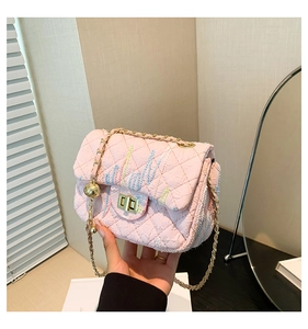 Detail of pink quilted handbag with colorful embroidery and golden chain strap