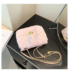 Close-up of pink quilted crossbody bag with colorful embroidery and golden chain strap