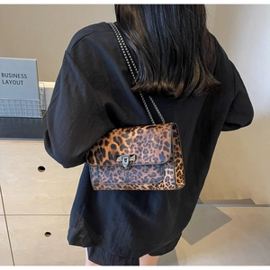 Detail of leopard print shoulder bag with black metal chain strap on model's shoulder