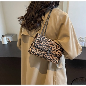 Close-up of leopard print shoulder bag with black metal chain on a khaki trench coat