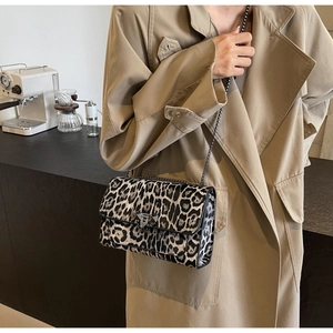 Detail of leopard print handbag featuring a trapezoidal metal clasp and chain strap