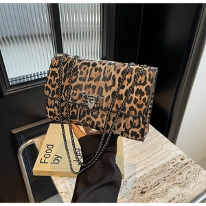 Close-up of leopard print shoulder bag with gold chain straps and V-shaped rivet buckle