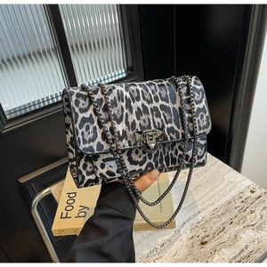 Detail of leopard print flap bag featuring a metal chain strap and studded buckle closure