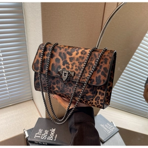 Detail of leopard print flap bag with dark metal chain strap and luxury push-lock closure