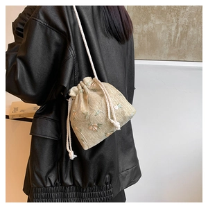 Dettaglio ricamo floreale su borsa a secchiello in tessuto beige con coulisse in cotone
